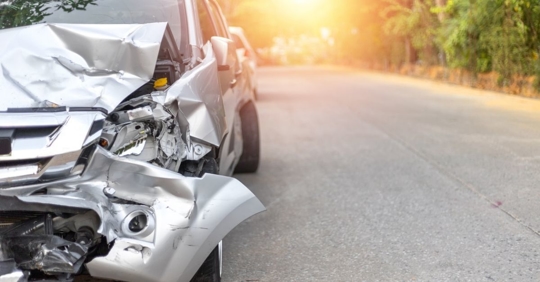 close up of a silver car with smashed front bumper