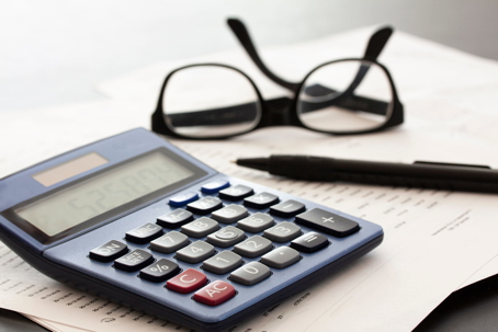 Calculator, eyeglasses, and pen resting on paperwork, representing the financial calculation of pain and suffering in a Florida personal injury claim.