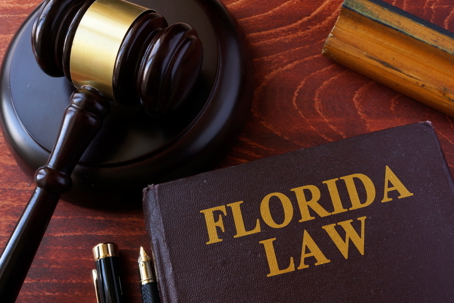 Judge’s gavel beside a Florida law book on a wooden desk.