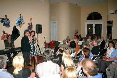 2 People singing together on stage with audience watching