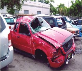 Totally damaged red pick up truck in a parking liot